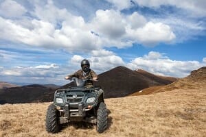 male rider sitting on ATV at mountain top